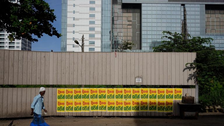 A Muslim man walks past a wall pasted with election...