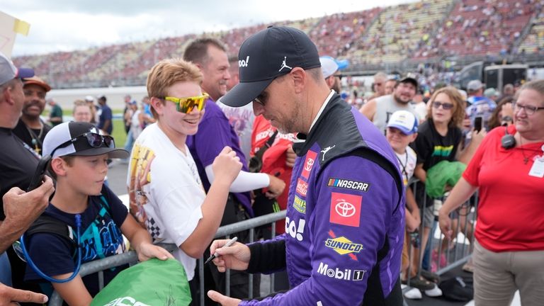 Denny Hamlin signs autographs before driver introductions of a NASCAR...