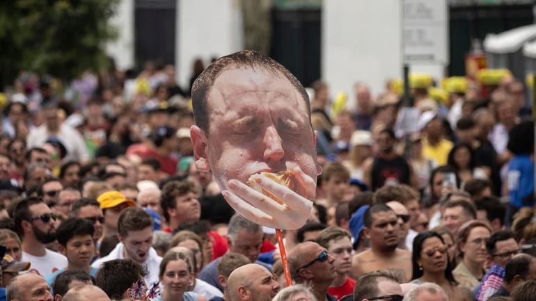 A person holds a sign with Joey Chestnut's face during...
