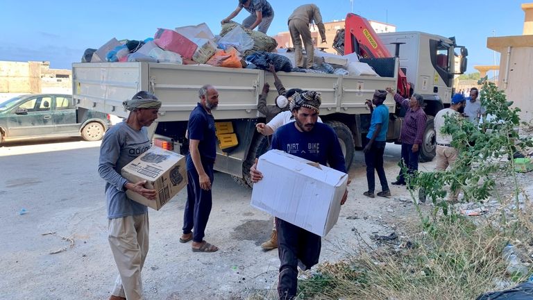 People deliver donated aid to a flash flood-destroyed city of...