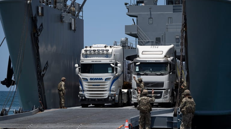 U.S. Army soldiers gestures as trucks loaded with humanitarian aid...