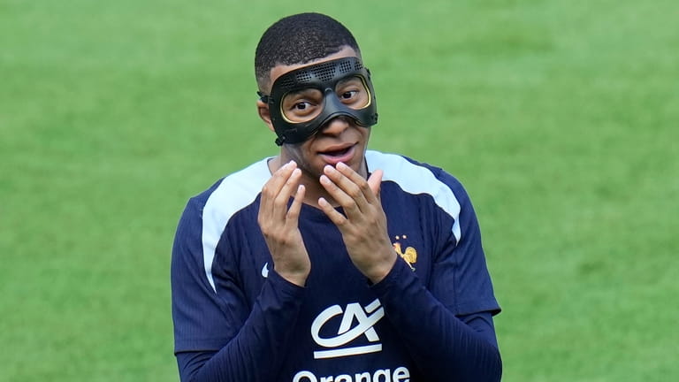 France's Kylian Mbappe gestures as he adjusts his face mask...
