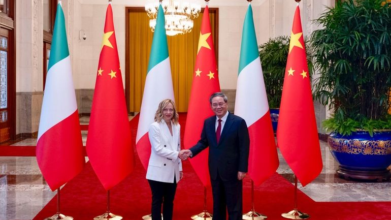 Italy's Prime Minister Giorgia Meloni shakes hands with Chinese Premier...