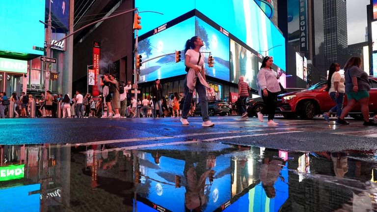 People walk through Times Square in New York, Friday, Aug....