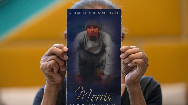 Natalia Mitchell, holds up a program memorializing her son, Morris...