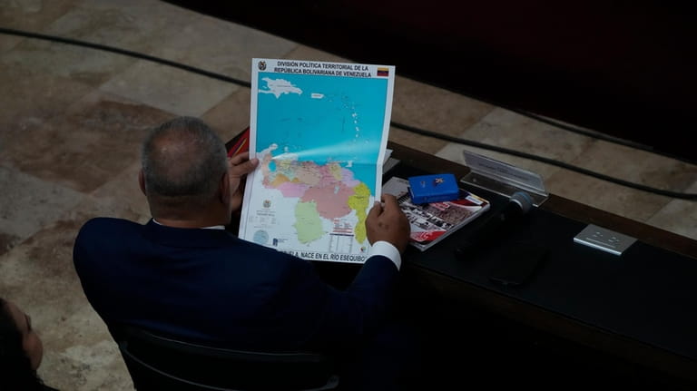 Venezuelan lawmaker Diosdado Cabello, looks at a new map of...