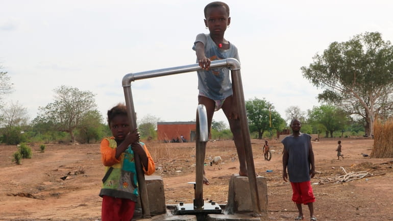 FILE- Children play on a water pump in an internally...