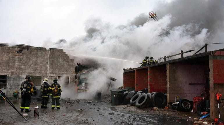 Firefighters work to extinguish a fire at a commercial building Sunday...