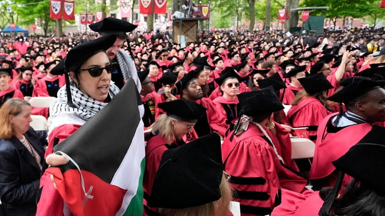 Graduating students chant as they depart commencement in protest to...