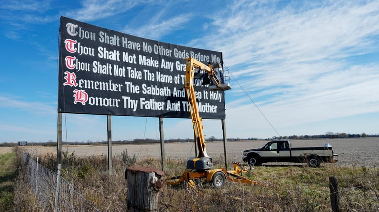 Workers repaint a Ten Commandments billboard off of Interstate 71...