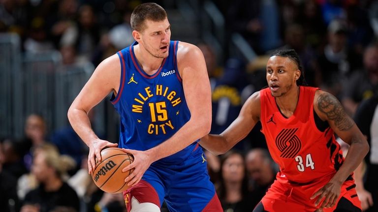 Denver Nuggets center Nikola Jokic, left, looks to pass the...