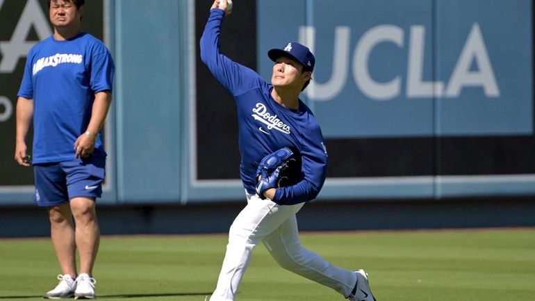 Los Angeles Dodgers starting pitcher Yoshinobu Yamamoto, right, throws in...