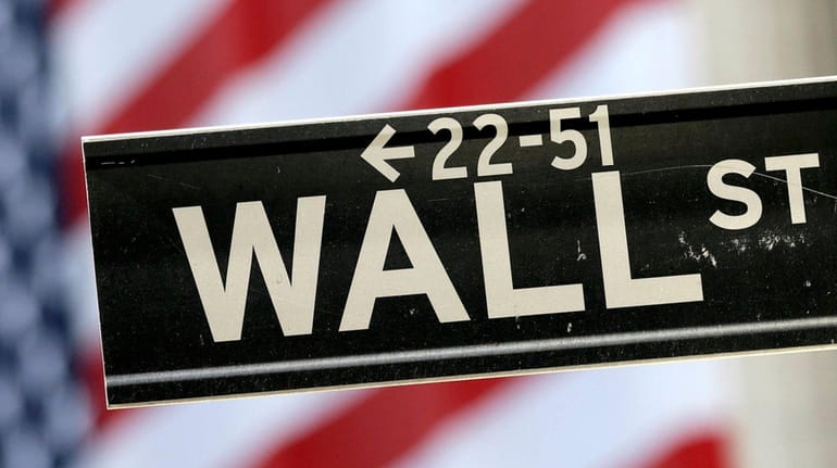 A Wall Street street sign is framed by an American...