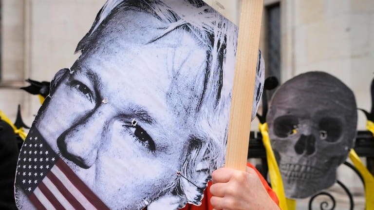 A demonstrator holds a Julian Assange mask outside the Royal...
