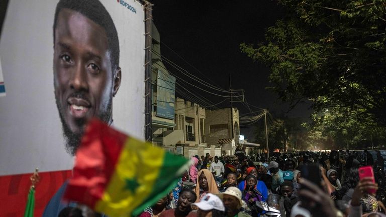 Supporters of presidential candidate Bassirou Diomaye Faye gather outside his...