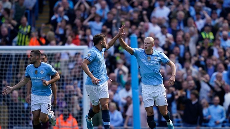 Manchester City's Erling Haaland, right, is congratulated by Ruben Dias...