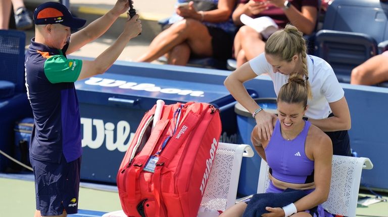 Maria Sakkari, of Greece, reacts as a trainer works on...