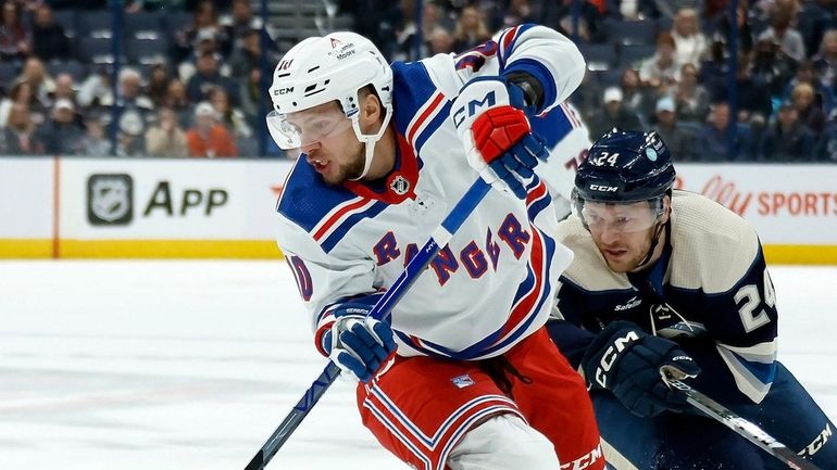 Artemi Panarin #10 of the Rangers keeps the puck away from...