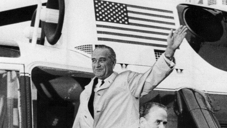 President Lyndon Baines Johnson waves to the crowd as he...