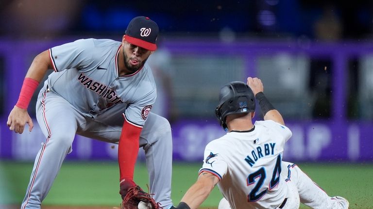 Washington Nationals second baseman Luis García Jr., left, tags out...