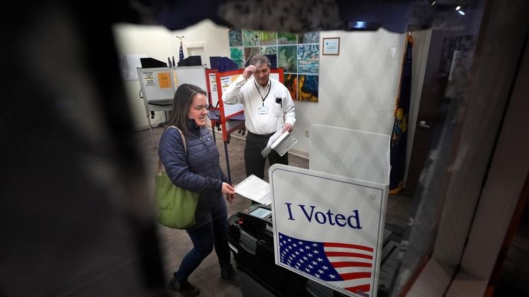 Amber Cutler casts her ballot as election official Monte Mason...