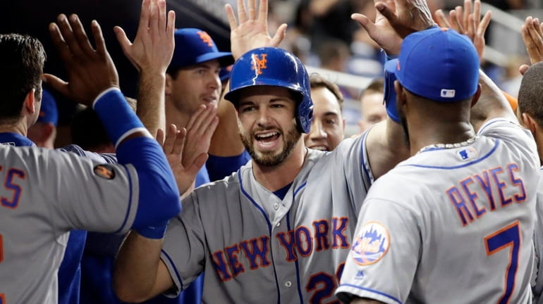 Mets catcher Kevin Plawecki is congratulated after scoring on a...