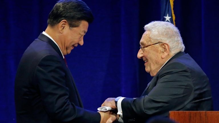 Chinese President Xi Jinping, left, shakes hands with former Secretary...