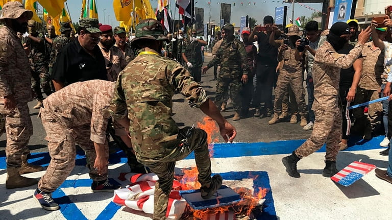 Popular Mobilization Forces burn representations of U.S. and Israeli flags...