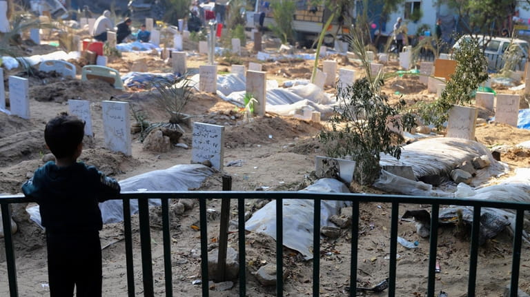A Palestinian child looks at the graves of people killed...
