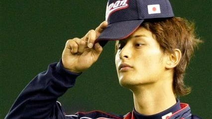 Team Japan pitcher Yu Darvish adjusts his cap in outfield...
