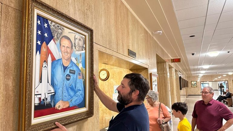 Brandon Levi hangs a portrait of former NASA astronaut James...