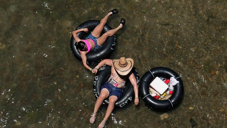 Tubers float the cool Comal River in New Braunfels, Texas,...