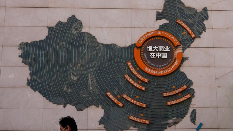 FILE- A woman walks past a map showing Evergrande development...