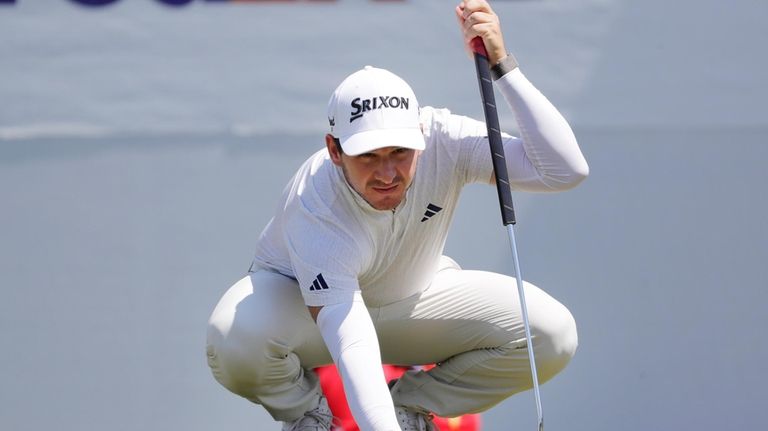 Alejandro Tosti places his ball on the 15th green before...