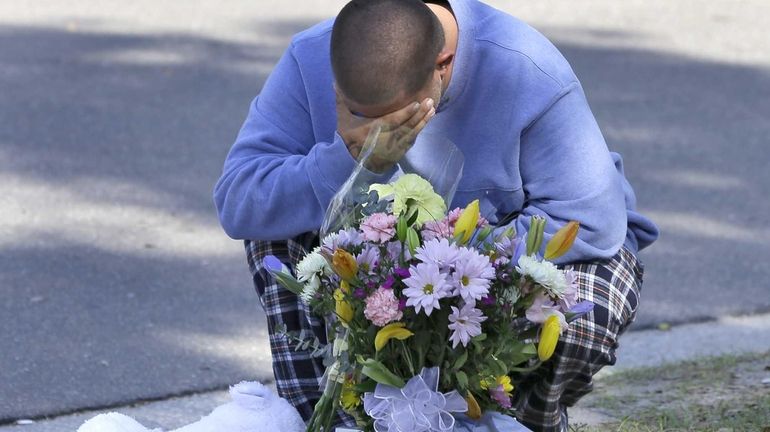 Jeremy Bush places flowers and a stuffed animal at a...