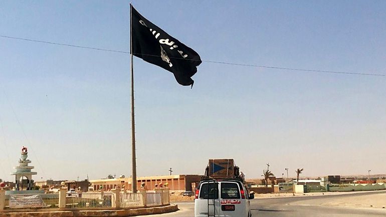 A motorist passes by a flag of the Islamic State...