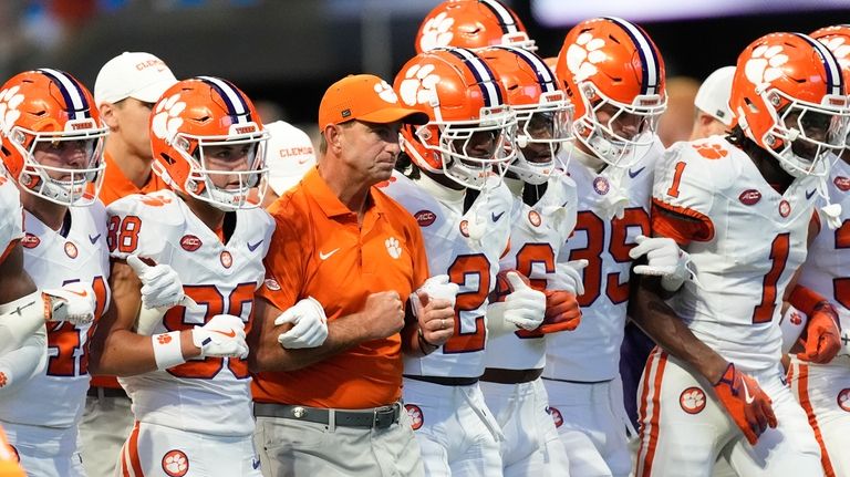 Clemson head coach Dabo Swinney, center, walks with his players...