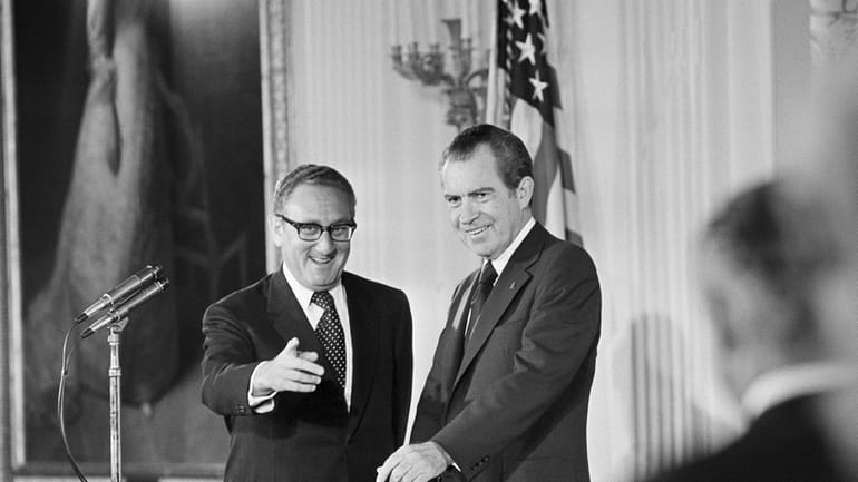 Secretary of State Henry Kissinger, left, gestures to the audience...