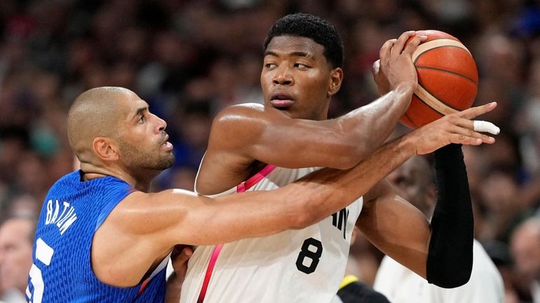 France's Nicolas Batum, left, reaches in on Japan's Rui Hachimura...