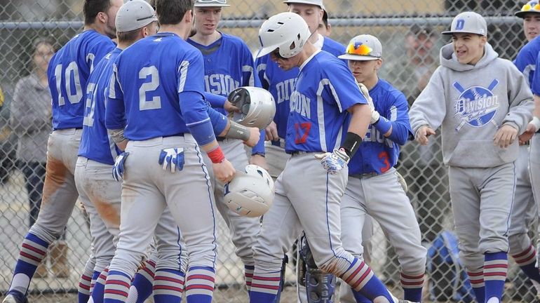 Division teammates greet catcher Mark Martinez at home plate after...