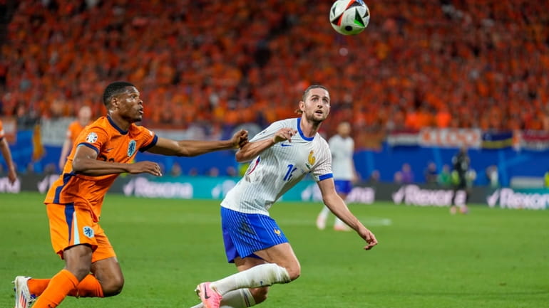 Denzel Dumfries of the Netherlands, left, duels for the ball...