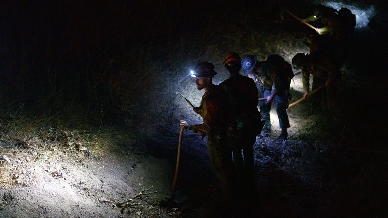 Firefighting hand crews cut lines against the advancing Line Fire...