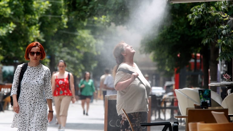 A woman tries to cool herself from a water mist...