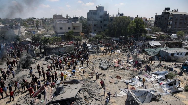 FILE -Palestinians inspect the damage at a site hit by...