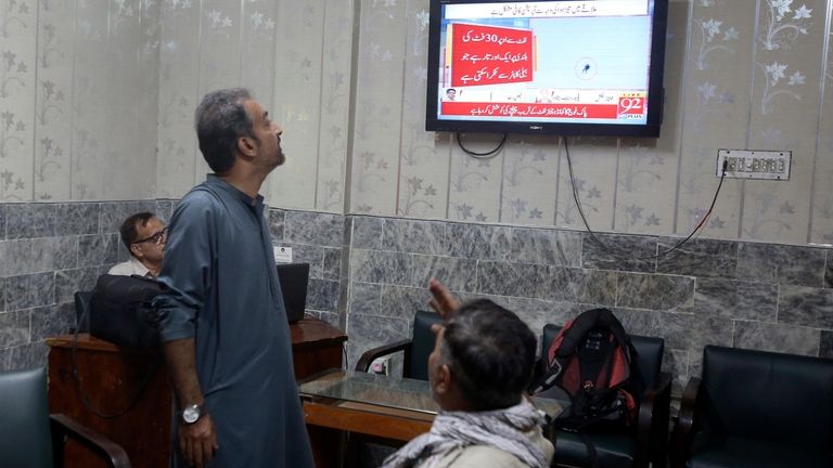 Members of the media watch a news channel airing news...