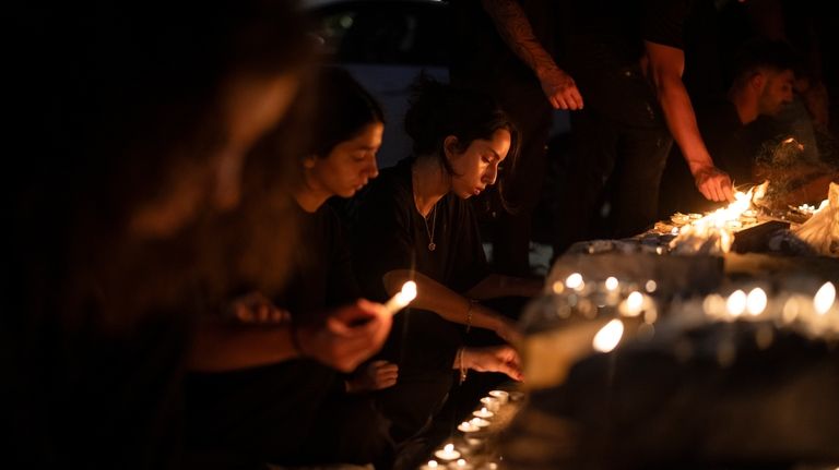 People light candles in memory of the children and teens...