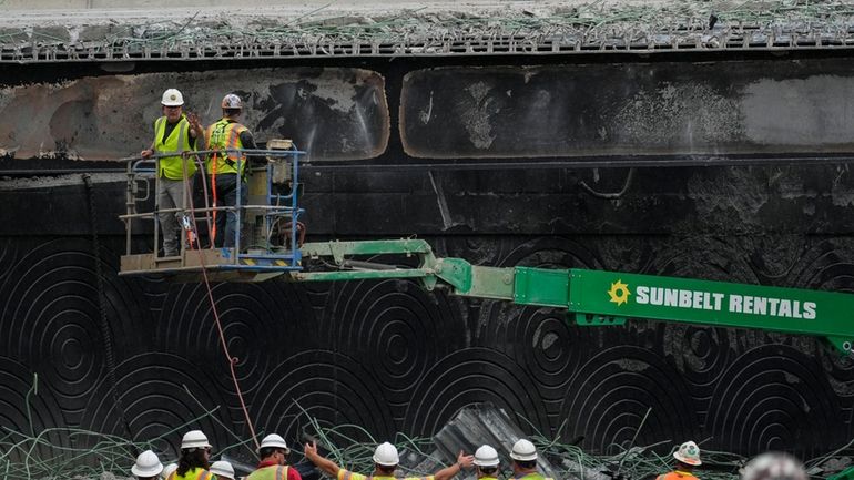 Crews work at the site of a collapsed section of...