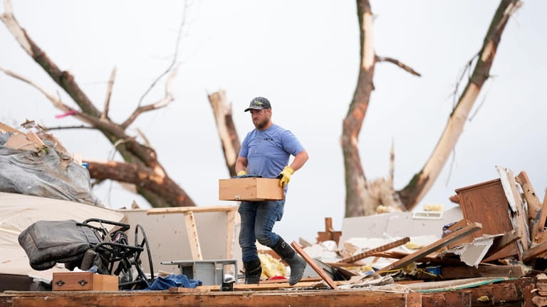 A man sorts through the remains of a tornado-damaged home,...