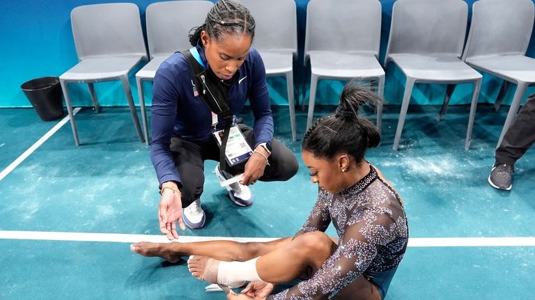 Simone Biles of United States, has her ankle taped after...