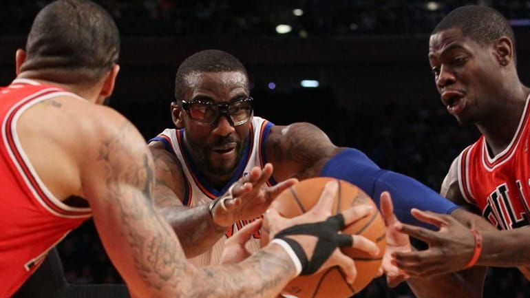 Amar'e Stoudemire loses the ball against Carlos Boozer and Derrick...